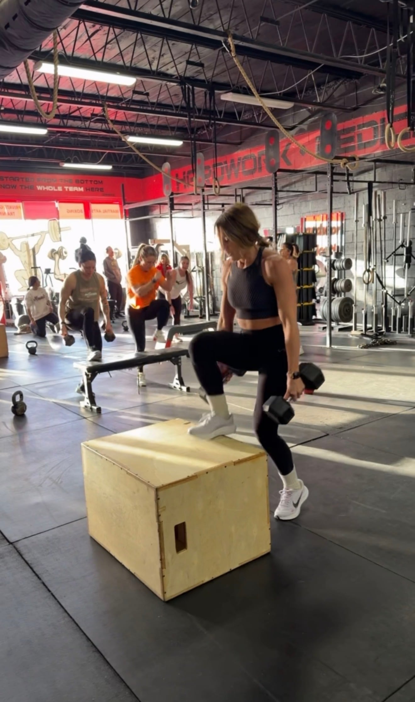 A member stepping onto a plyo box while others lunge behind during a strength and conditioning session at MPower Gym & Academy